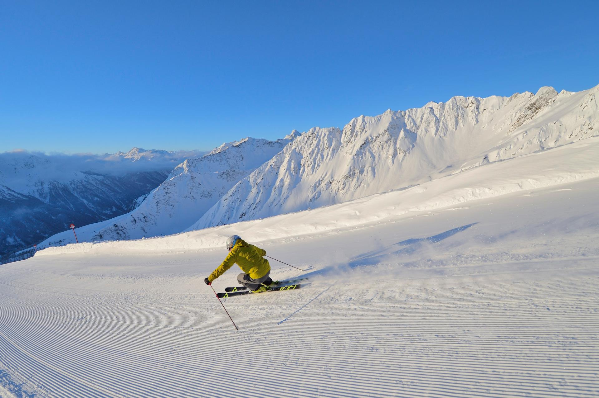 Skiier skiing down a freshly groomed piste at sunrise in Kappl