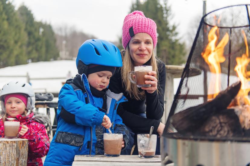 family drinking hot chocolate around fire